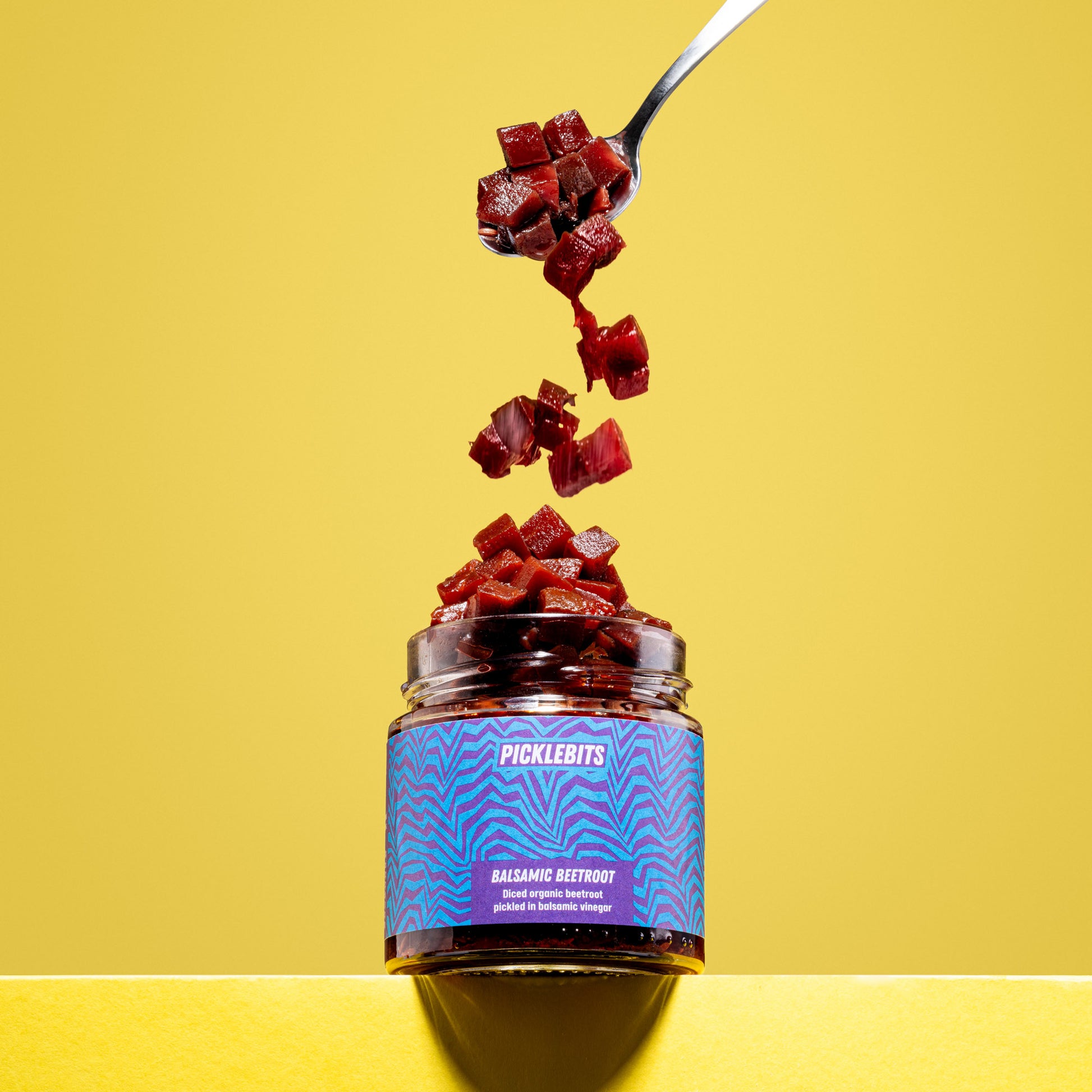 Jar of organic pickled beetroot with balsamic, beets tumbling on yellow background