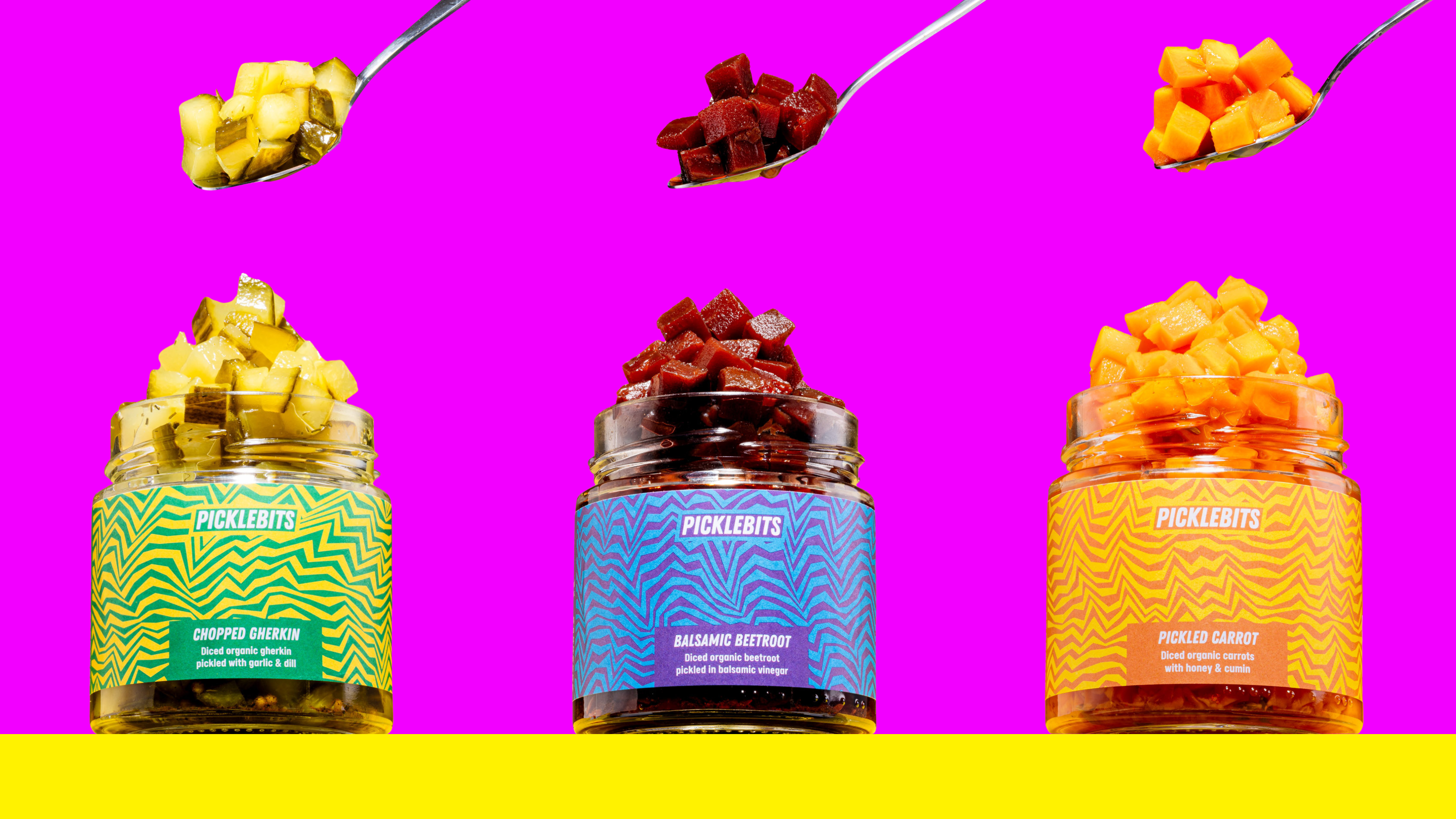 Three jars of organic chopped pickles with colorful labels on a pink and yellow background.